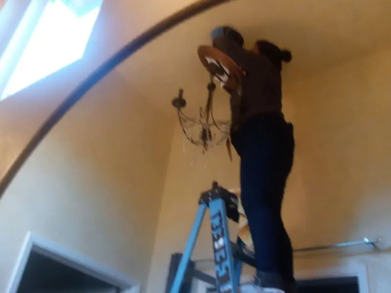 Electrician installing a chandelier in a Swanton residence